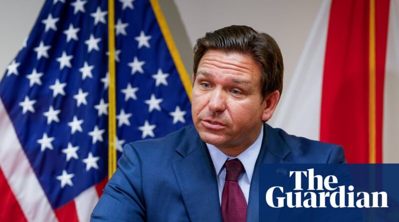 Governador Ron DeSantis em evento oficial com bandeiras dos EUA e Flórida