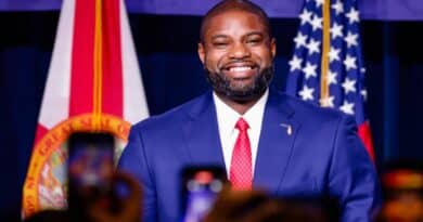 Byron Donalds em evento político em Miami com bandeiras da Flórida e dos EUA