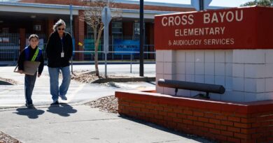 Entrada de escola primaria na Florida com estudante e adulto caminhando