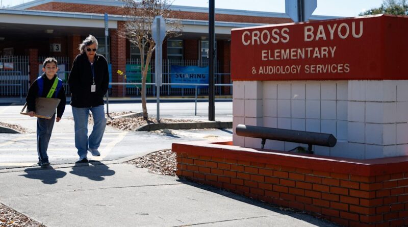 Entrada de escola primaria na Florida com estudante e adulto caminhando