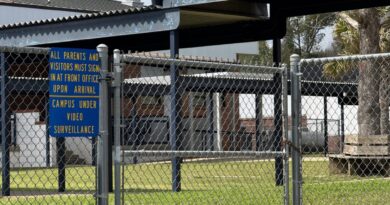 Entrada de escola na Flórida com cerca de seguranca e placa de vigilancia por video