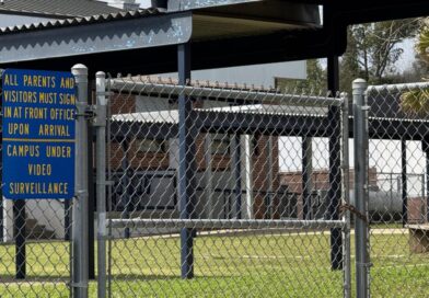 Entrada de escola na Flórida com cerca de seguranca e placa de vigilancia por video