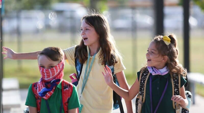 Criancas com mochilas caminham para a escola na Florida no primeiro dia de aula